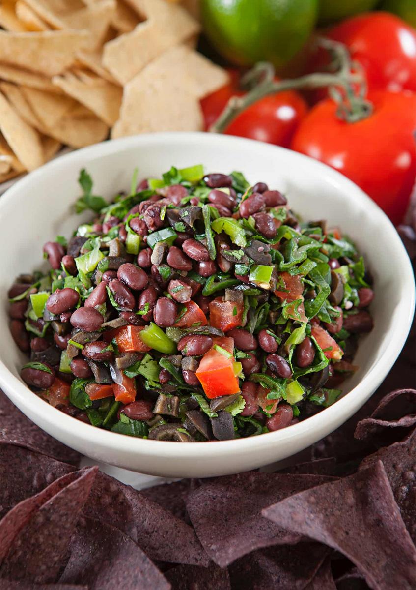 Bowl of black bean salsa in a white bowl on a bed of black and white tortilla chips